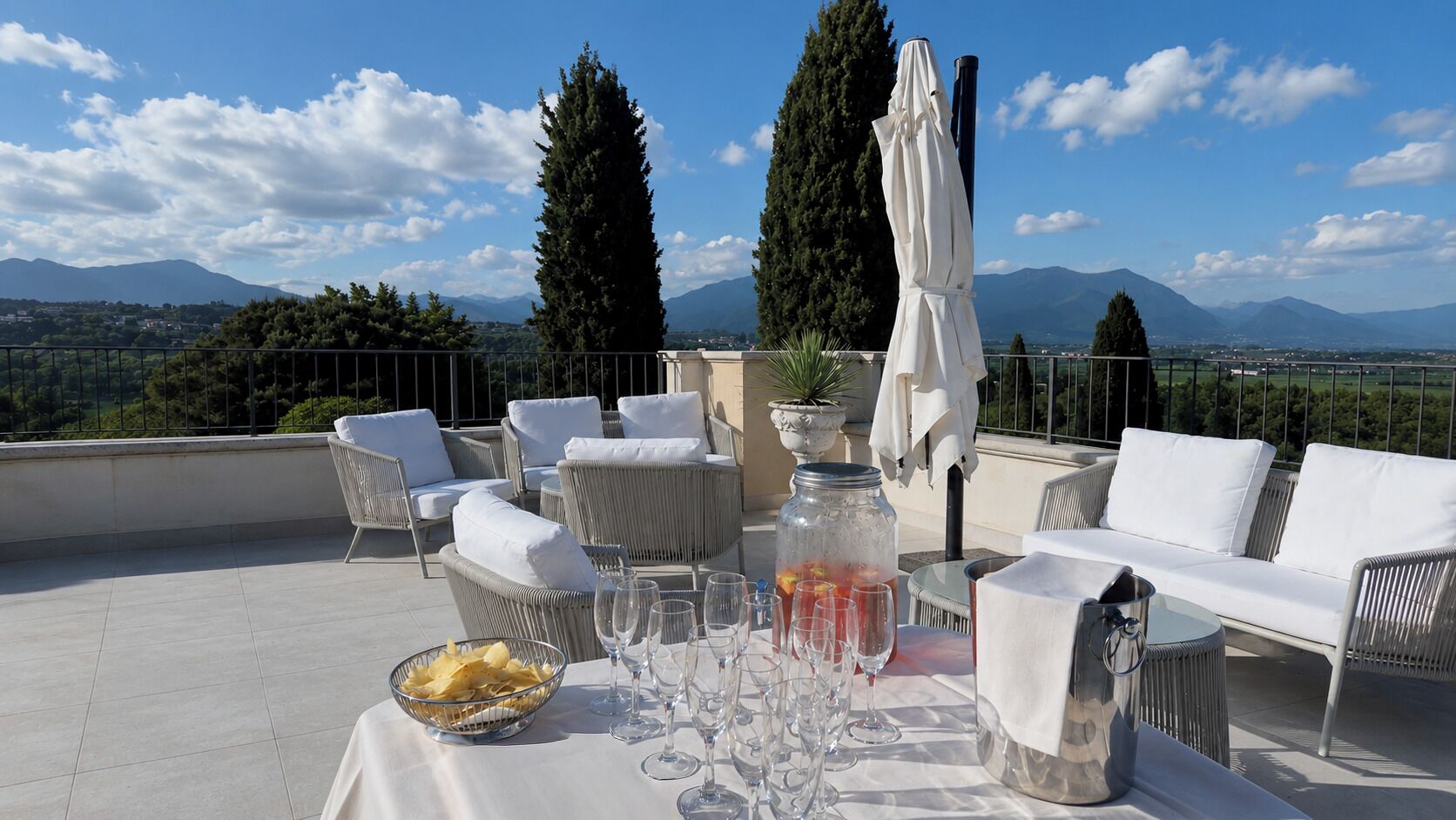 A rooftop terrace with outdoor seating, a table set for dining, and a scenic mountain view.