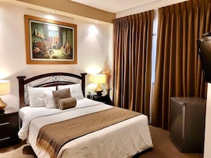 A hotel room with a large bed, a painting on the wall, a desk with a lamp, and a television. - Casa Bella Boutique Hotel San Isidro (Lima)