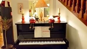 A grand piano with sheet music, a mirror, and decorative items on a black piano stand.