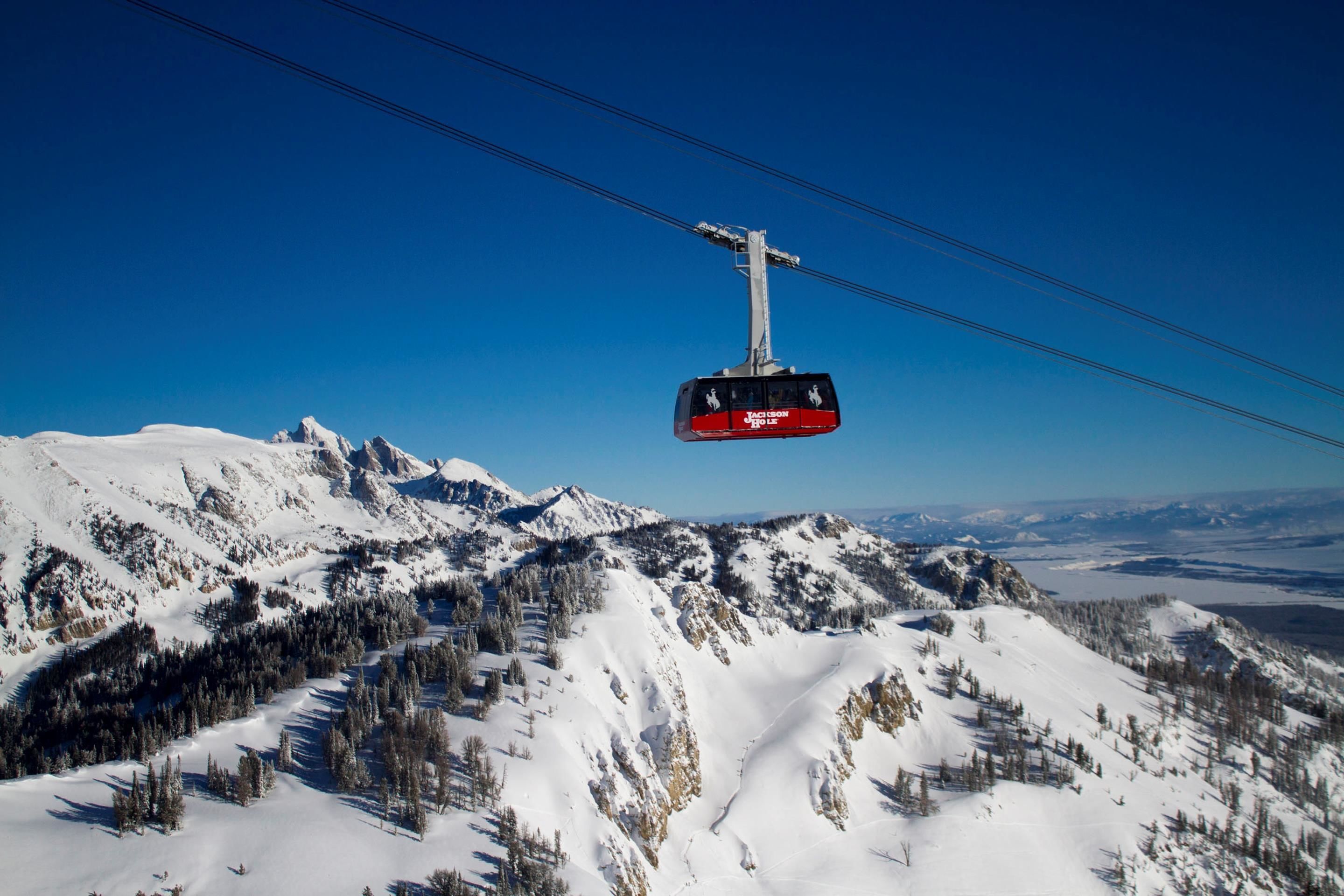 A cable car moving over a snowy mountain landscape.