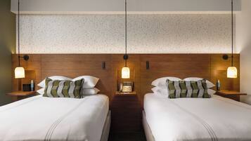 A hotel room with two beds, wooden headboard, nightstands with lamps, and a patterned wall.