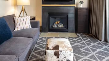 Una sala moderna con sofá, un reposapiés estampado, chimenea y televisor.