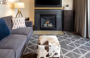 Una sala moderna con sofá, un reposapiés estampado, chimenea y televisor.