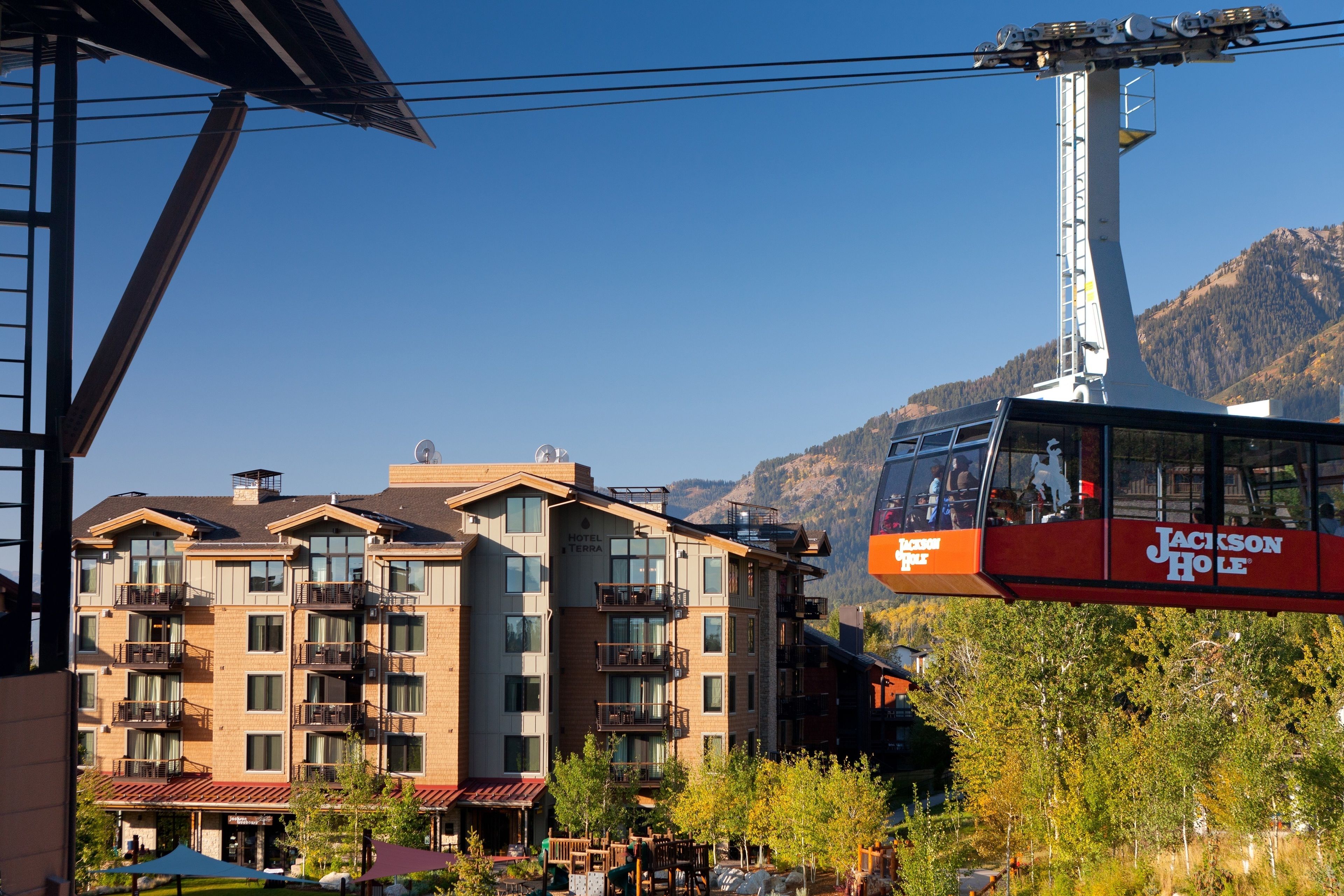 A multi-story hotel with balconies, a ski lift, and a mountainous backdrop.
