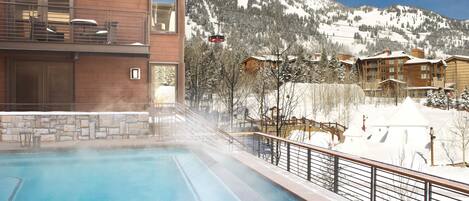 A pool area with a view of a mountain and ski resort buildings.