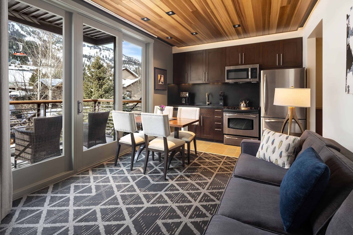A modern kitchen with dark cabinets, stainless steel appliances, and a dining area with a table and chairs.