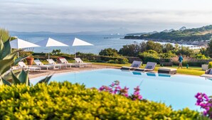 A pool with lounge chairs and umbrellas, surrounded by greenery and a view of the sea. - L'Ea Bianca Luxury Resort (Arzachena)