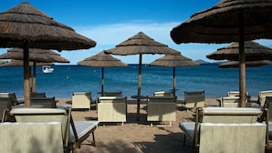 A beach with thatched umbrellas and lounge chairs facing the sea. - L'Ea Bianca Luxury Resort (Arzachena)