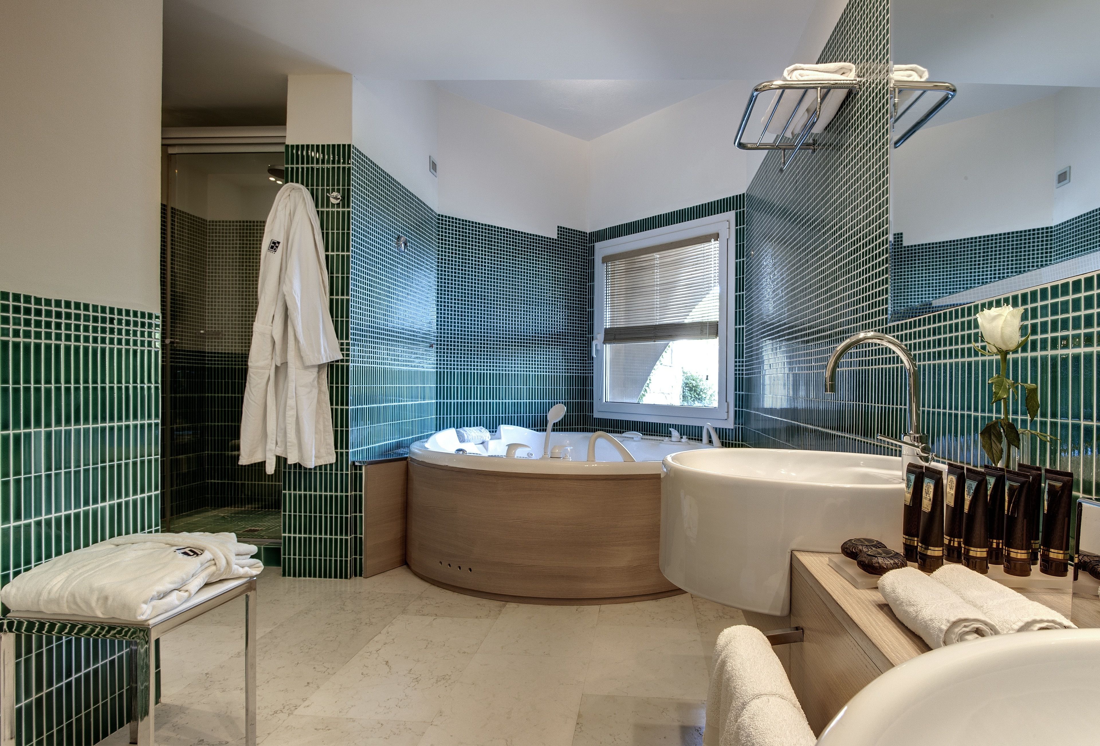 Une salle de bain moderne dotée d’une grande baignoire, d’une douche séparée et d’un meuble-lavabo avec des articles de toilette.