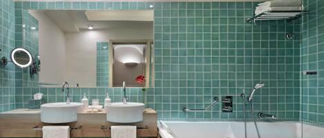 A modern bathroom with two sinks, a large bathtub, and a mirror.