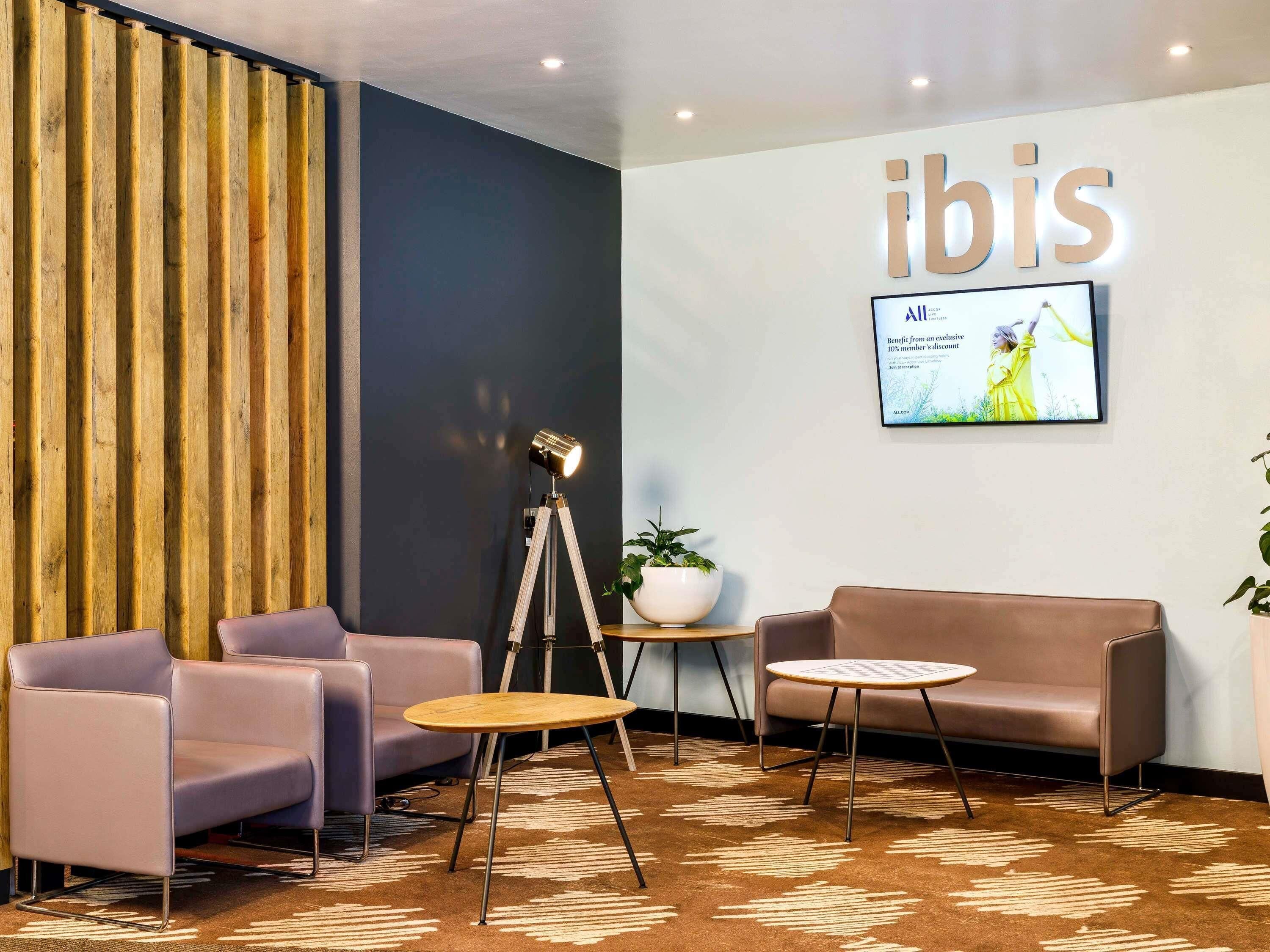 A modern lobby with a seating area, a mounted television, and a wooden panel wall.