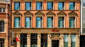 A two-story hotel with a classic facade, multiple windows, and a prominent 'ibis HOTEL' sign.