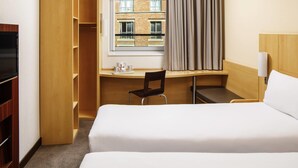 A hotel room with a bed, a desk with a chair, a TV, and a window with curtains. - ibis Nottingham Centre (Nottingham)