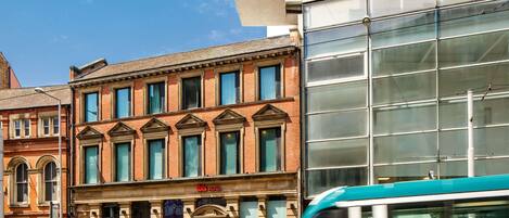 A modern building with a prominent 'ibis HOTEL' sign, a traditional brick facade, and a glass entrance.