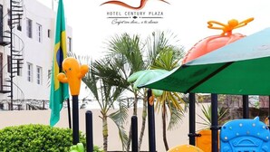 Ein Spielplatz mit verschiedenen Spielgeräten, darunter Rutschen und Kletterelementen, umgeben von Grünflächen und einer Fahne.
