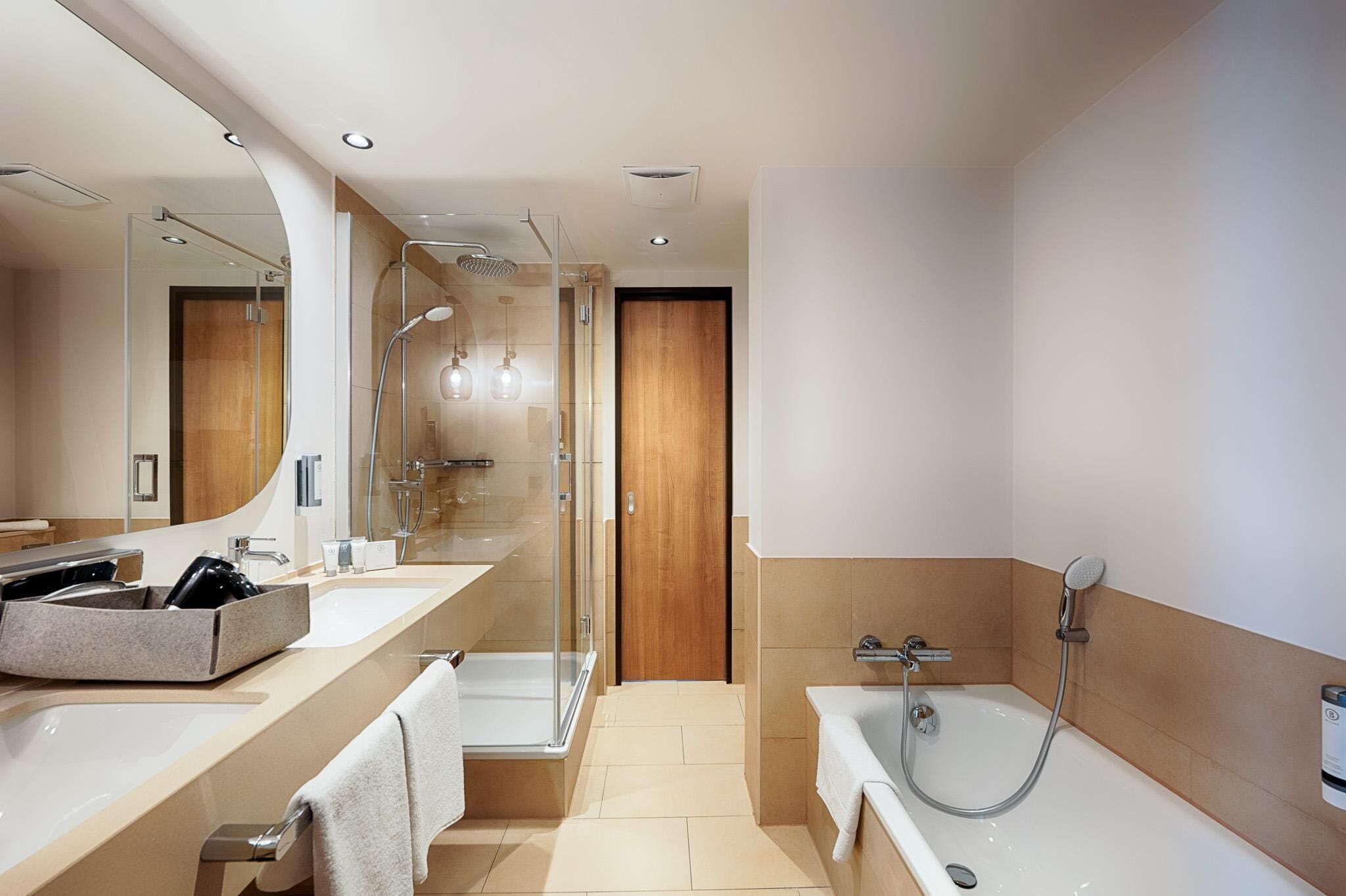 A modern bathroom with a glass-enclosed shower, a bathtub, and a vanity with a sink and mirror.