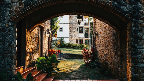 An arched stone entrance leading to a courtyard with steps and potted plants. - Los Mandarinos Hotel Boutique & Spa (El Valle de Anton)