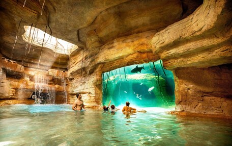 A natural rock formation with a clear water pool and a viewing area.