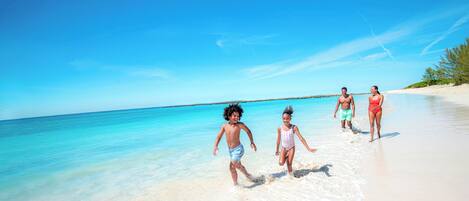 A beach scene with clear turquoise water and white sand.