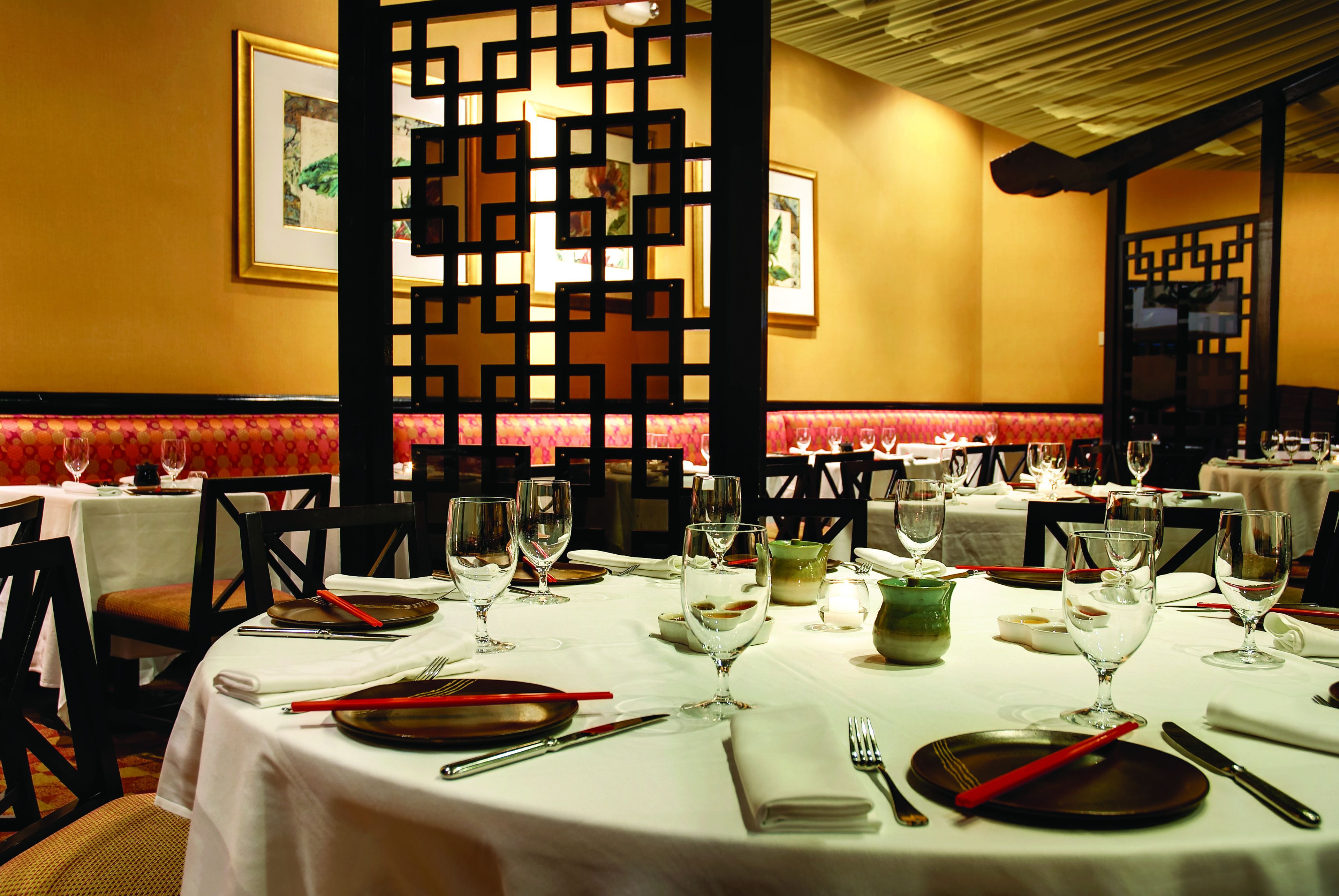 A restaurant with round tables set for dining, complete with plates, cutlery, and glasses.
