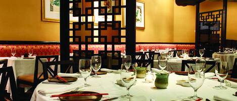 A restaurant with round tables set for dining, complete with plates, cutlery, and glasses.