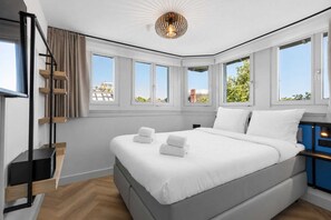 A modern bedroom with a large bed, a staircase, and multiple windows. - Dutch Design Hotel Vondelpark (Amsterdam)