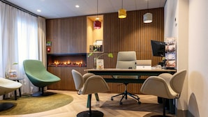 A modern office with a wooden panel wall, a desk with two chairs, a television, and a fireplace. - Dutch Design Hotel Vondelpark (Amsterdam)