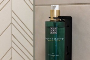A green bottle of shampoo and shower gel on a black shelf. - Dutch Design Hotel Vondelpark (Amsterdam)