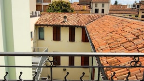 A courtyard with a wooden bench, a bicycle, and a building with a tiled roof.