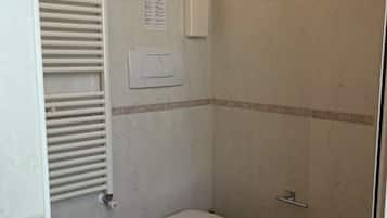 Une salle de bain comprenant des toilettes, un bidet et un espace douche.