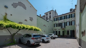 A narrow street with parked cars and a building with a large mural.