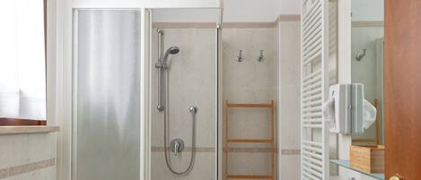 Une salle de bain moderne avec une douche à parois de verre, un lavabo et un miroir.