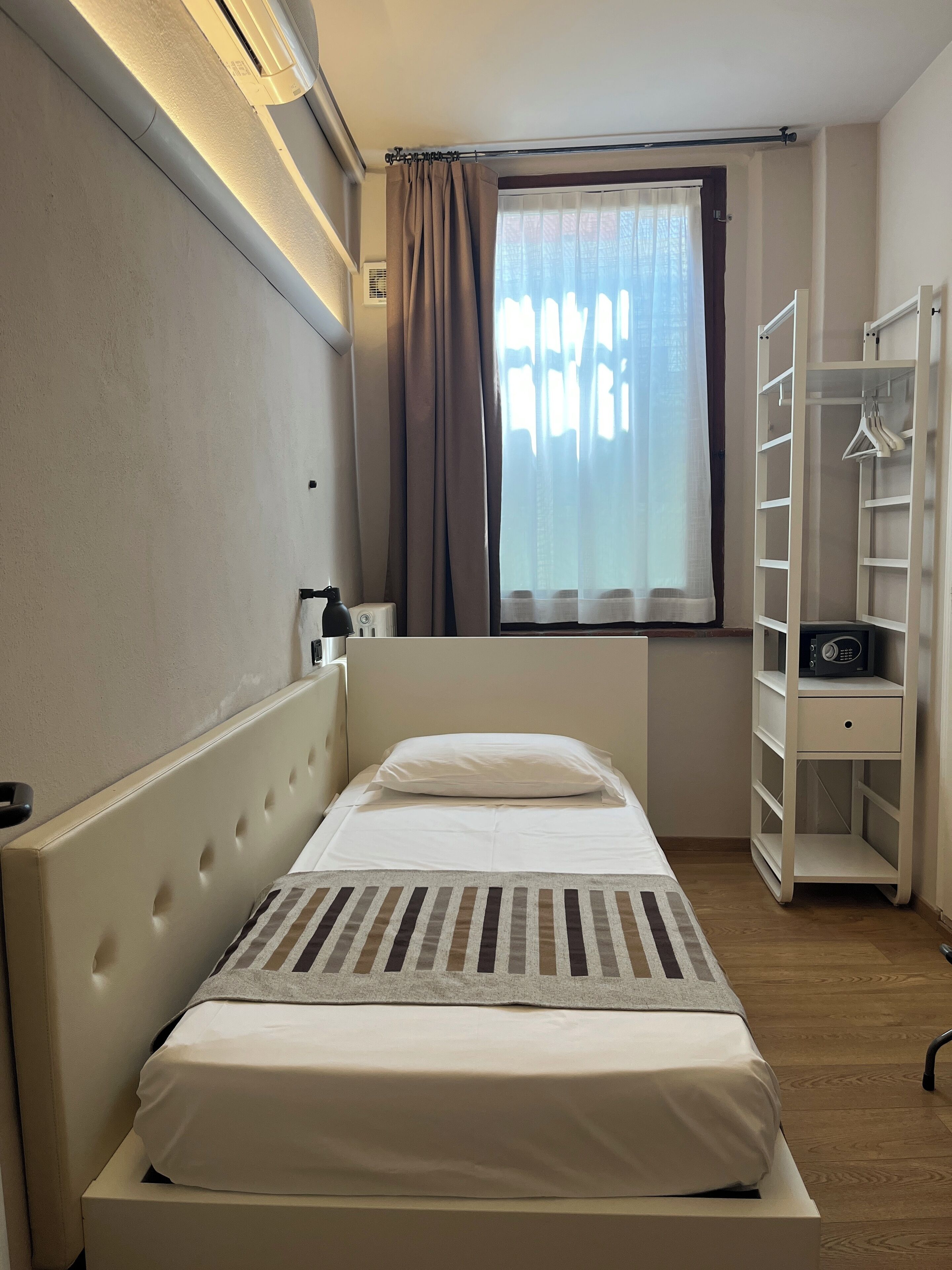 A neatly arranged bedroom with a bed, bedside table, and a wardrobe.