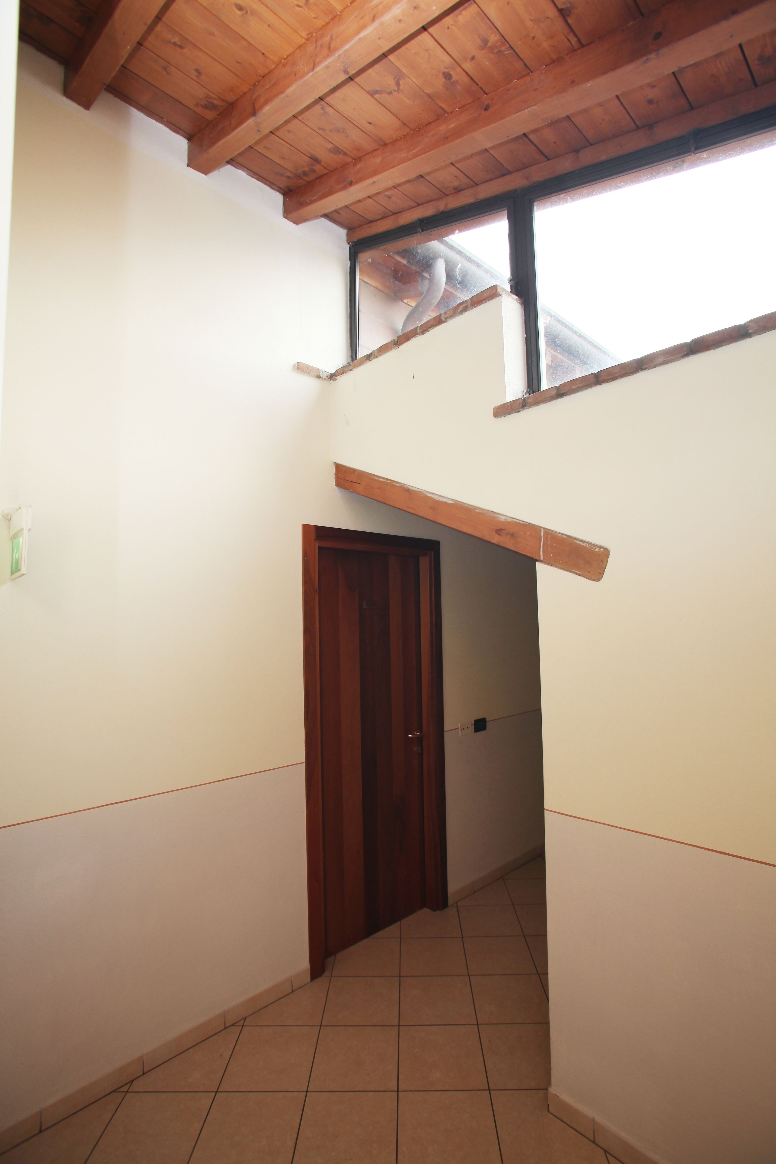 A narrow hallway with a wooden ceiling and a door at the end.