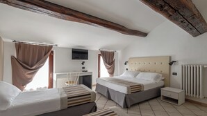 A bedroom with two beds, a desk, a TV, and a radiator.
