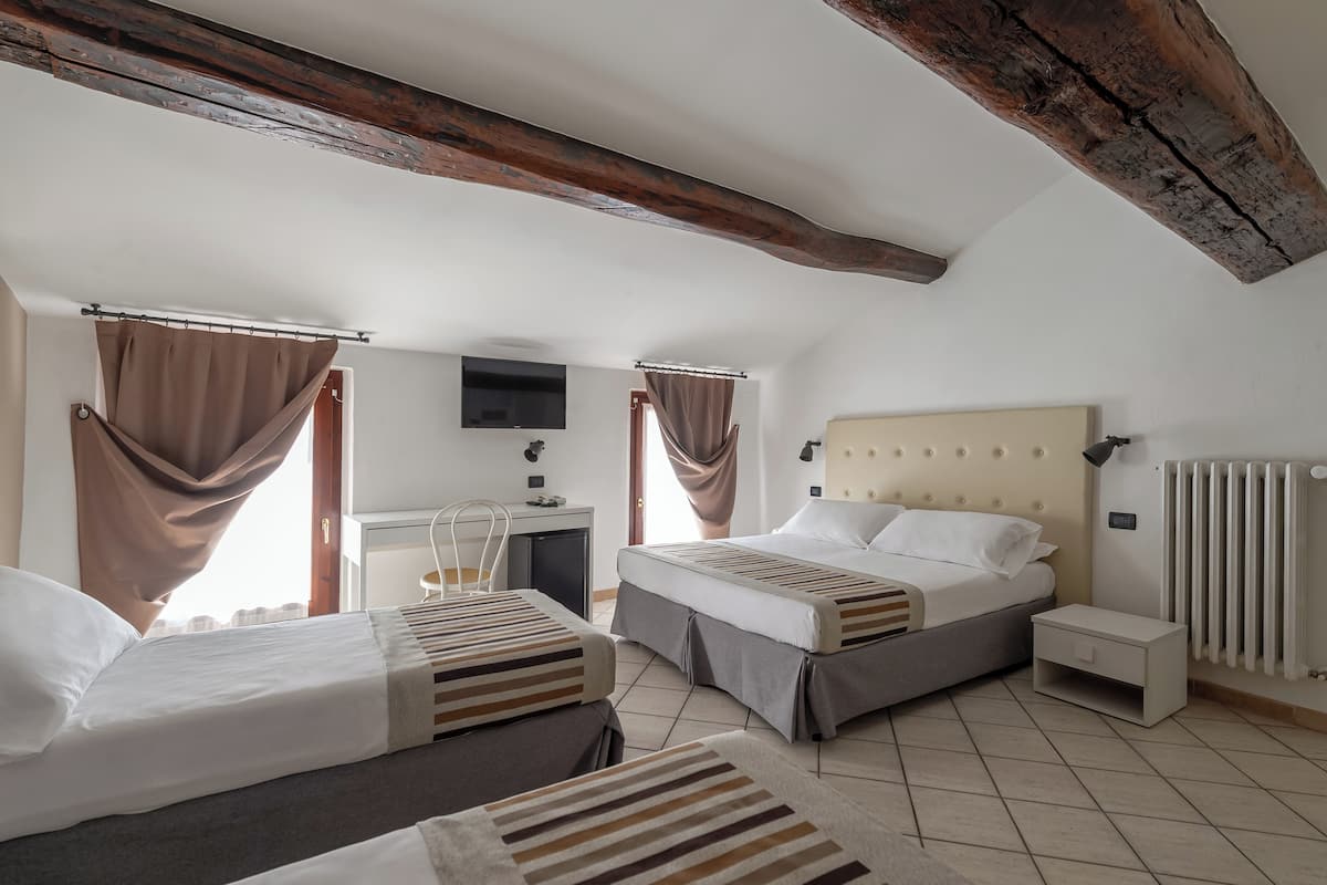 A bedroom with two beds, a desk, a TV, and a radiator.