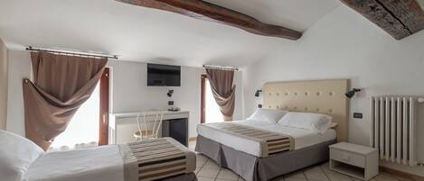 A bedroom with two beds, a desk, a TV, and a radiator.