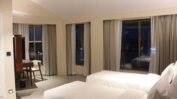 A hotel room with two beds, a desk, and a chair.