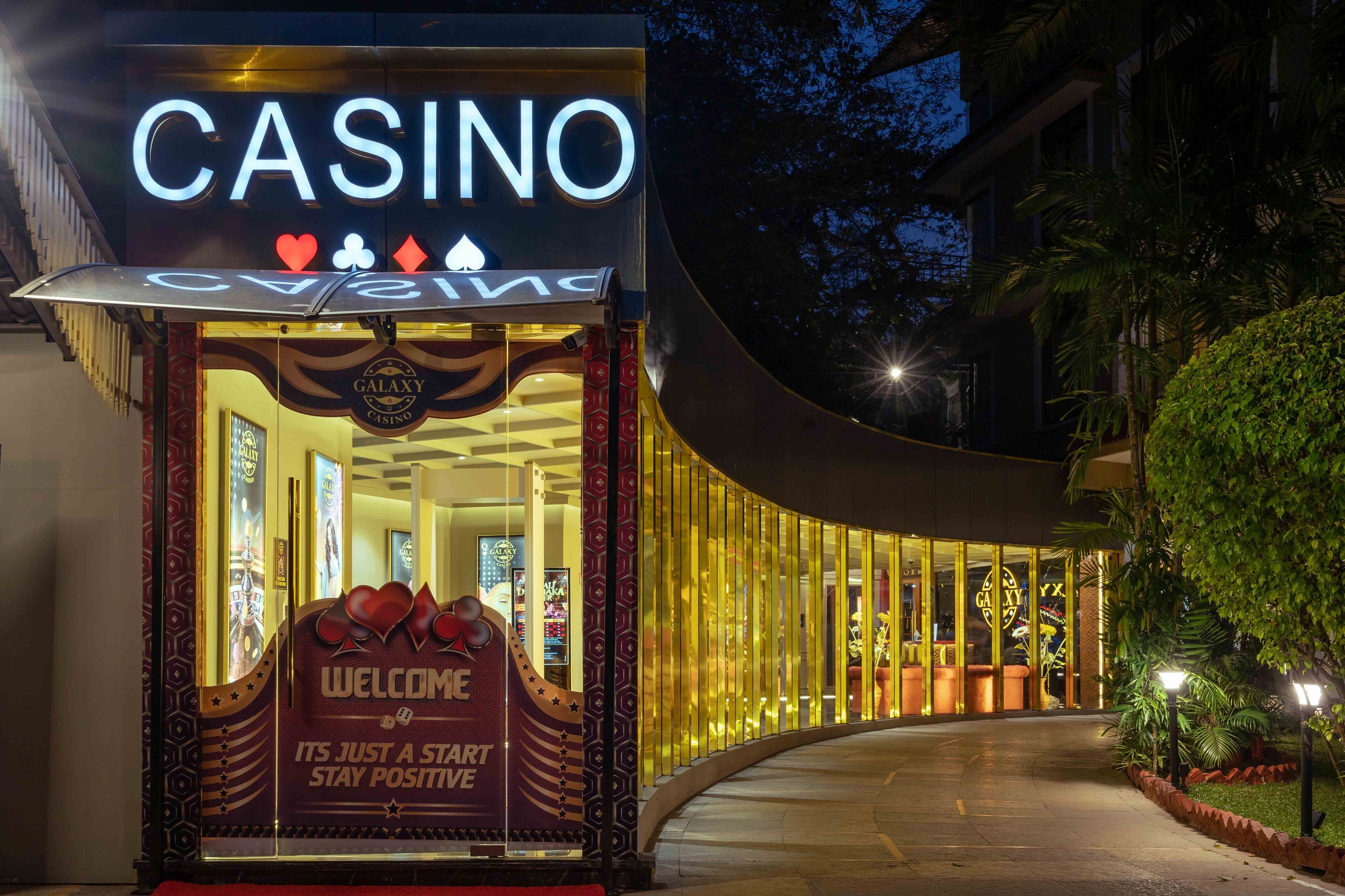 A casino entrance with a prominent sign, a curved glass facade, and a welcoming sign.