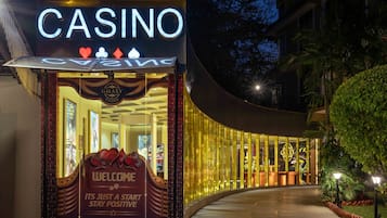 A casino entrance with a prominent sign, a curved glass facade, and a welcoming sign.