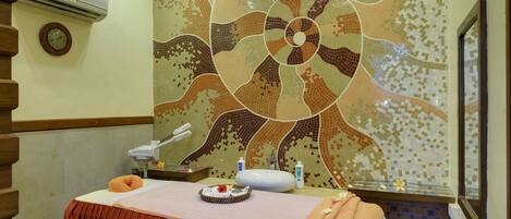 Un cuarto de spa con una camilla de masaje, un reloj y una pared decorativa con mosaicos.