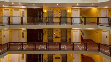 Interior de un hotel con varios niveles, ascensores y salidas de emergencia.