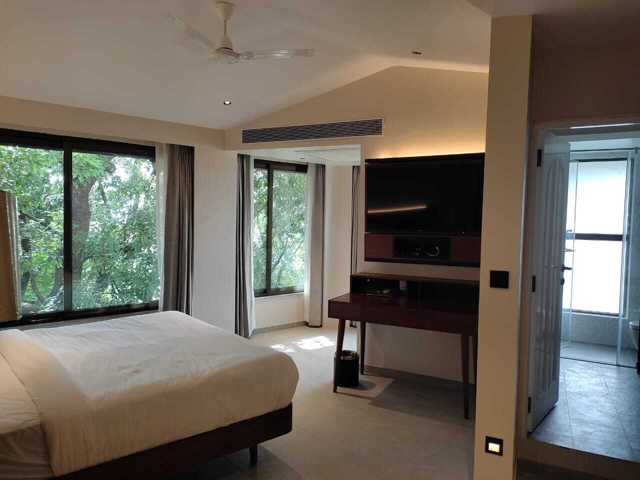 A modern hotel room with a large bed, a desk, and a flat-screen TV.