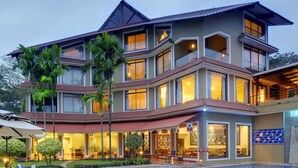 Ein mehrstöckiges Hotel mit Pool, großen Fenstern und einem gepflegten Garten.