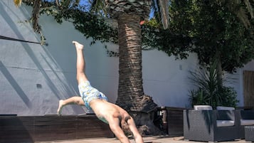 Una piscina al aire libre, sombrillas, sillones reclinables de piscina