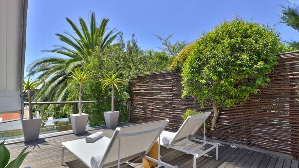 A wooden deck with two white lounge chairs and a potted plant. - Cape Diem Lodge  (Cape Town)