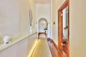 A hallway with a wooden floor, white walls, and a white door at the end. - Cape Diem Lodge  (Cape Town)