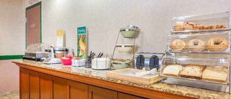 A breakfast buffet with various food items, a coffee machine, and a fruit bowl.