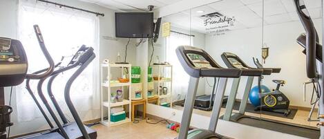 A gym with treadmills, a stationary bike, and a mirror on the wall.