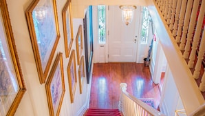 A grand staircase with red carpeted steps, white balusters, and a white railing.